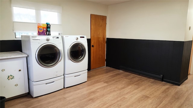 clothes washing area featuring a baseboard heating unit, light hardwood / wood-style floors, and independent washer and dryer