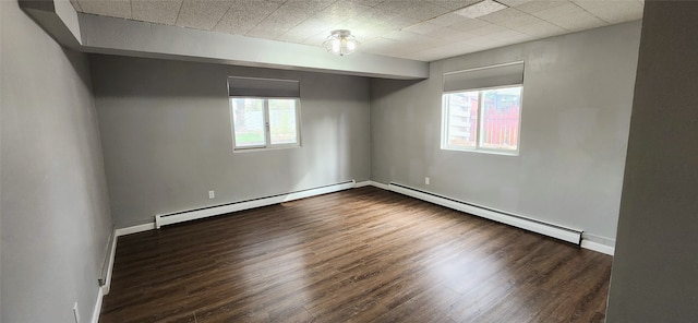 spare room with plenty of natural light, dark hardwood / wood-style flooring, and a baseboard heating unit