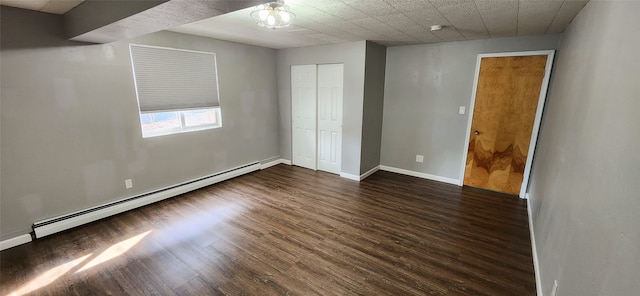 unfurnished bedroom with a baseboard radiator, a closet, and dark wood-type flooring