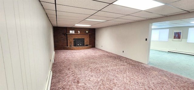 basement featuring carpet, a drop ceiling, a wood stove, and a baseboard radiator