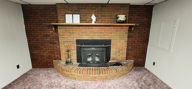 interior details with carpet floors, a drop ceiling, and a wood stove