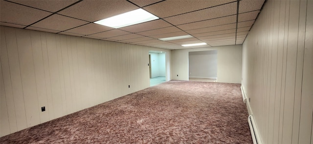 carpeted empty room with wooden walls and a drop ceiling