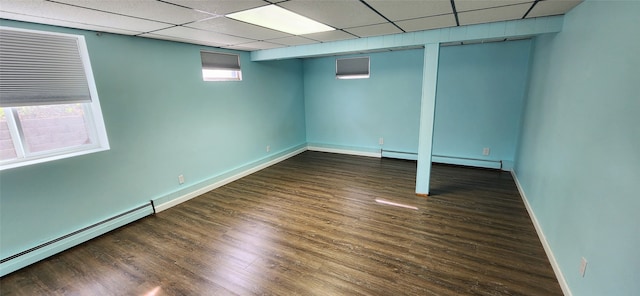 basement with baseboard heating, plenty of natural light, and dark wood-type flooring