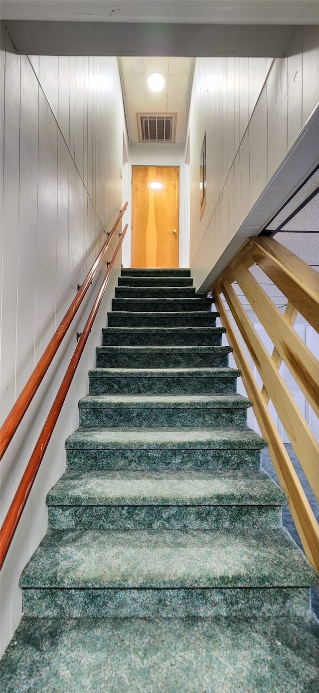 stairway featuring wooden walls