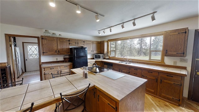 3653 Sophie Lake Rd, Eureka, MT 59917 - kitchen featuring black appliances, tile counters, light wood-type flooring, and brown cabinetry