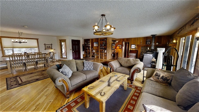 3653 Sophie Lake Rd, Eureka, MT 59917 - living area with a chandelier, a textured ceiling, light wood-style flooring, and a wood stove