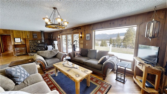 3653 Sophie Lake Rd, Eureka, MT 59917 - living area with a wood stove, wood walls, a textured ceiling, a chandelier, and wood finished floors