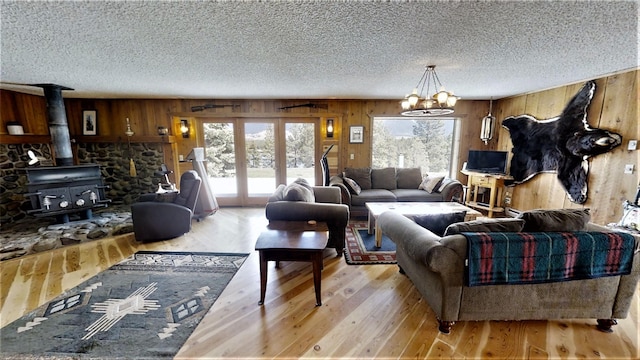 3653 Sophie Lake Rd, Eureka, MT 59917 - living room featuring wooden walls, plenty of natural light, light wood-style flooring, a textured ceiling, and a wood stove