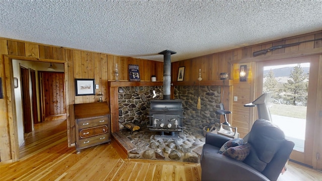 3653 Sophie Lake Rd, Eureka, MT 59917 - living area featuring wooden walls, a wood stove, a textured ceiling, and light wood-type flooring