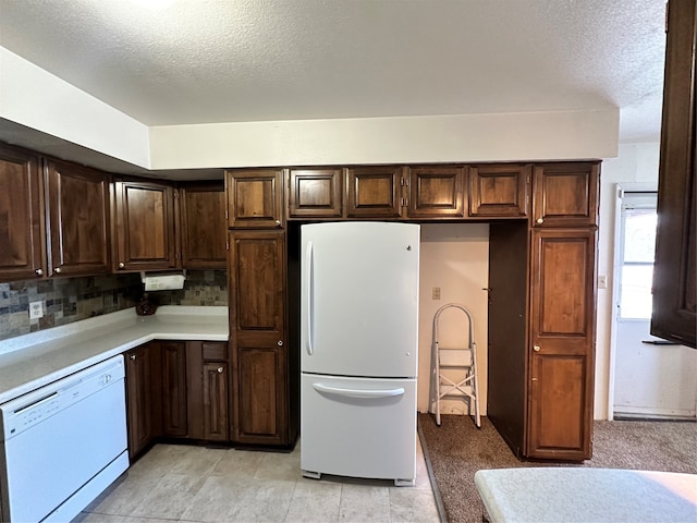 kitchen with white appliances, backsplash, and dark brown cabinetry