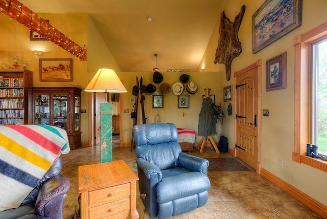 living room featuring baseboards, tile patterned flooring, and high vaulted ceiling