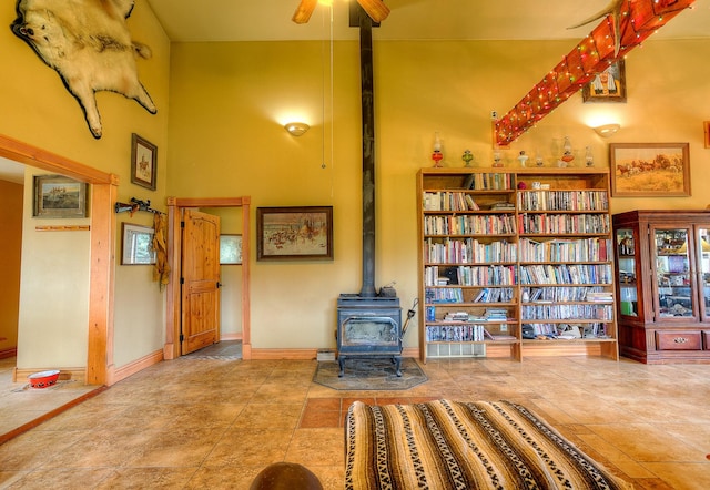 interior space with a ceiling fan, a towering ceiling, and a wood stove