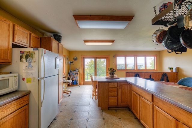 kitchen with a healthy amount of sunlight, white appliances, and light tile floors