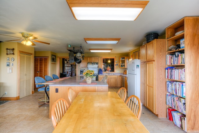 dining space with ceiling fan and light tile flooring