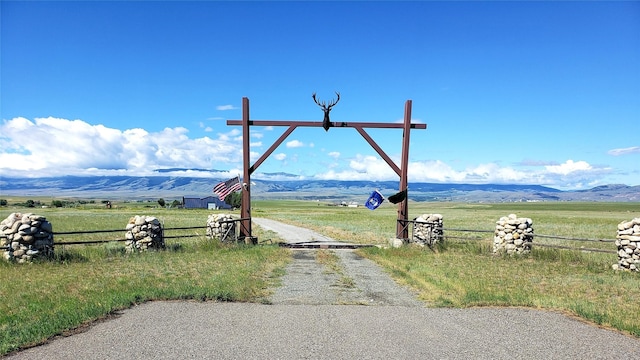 view of road featuring gravel driveway, a rural view, and a mountain view