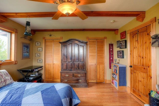 bedroom with beam ceiling, light wood finished floors, and a ceiling fan