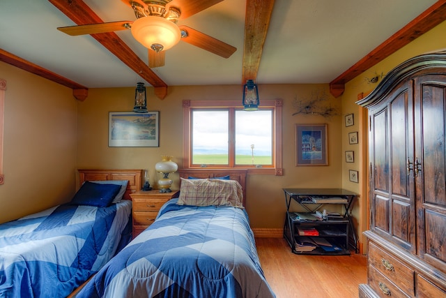 bedroom featuring beamed ceiling, light hardwood / wood-style floors, and ceiling fan