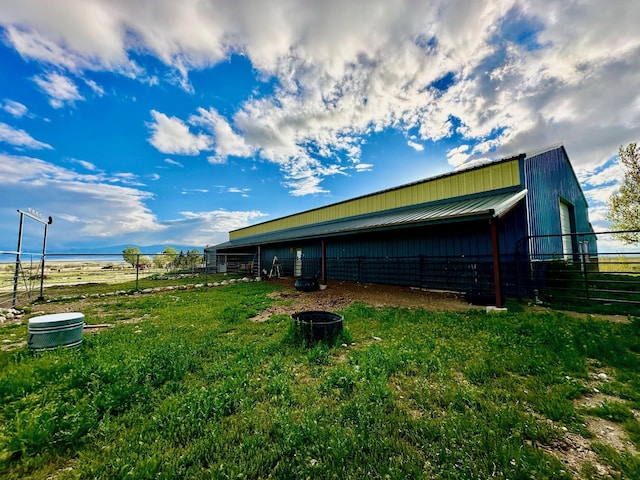 view of side of property with an outdoor structure, fence, and metal roof