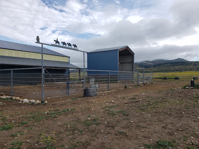 view of horse barn with an outdoor structure, a mountain view, and a rural view