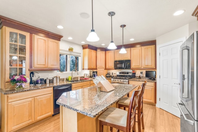 kitchen with light hardwood / wood-style floors, a kitchen island, black appliances, sink, and pendant lighting