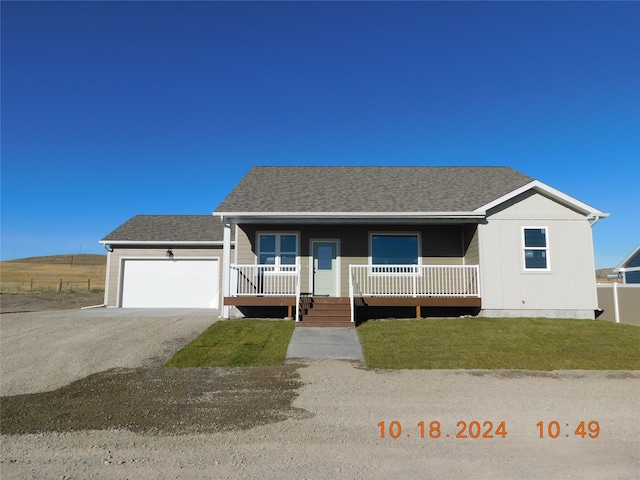 view of front of house featuring a front yard, a garage, and a porch