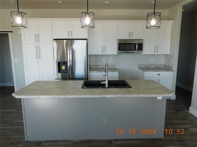 kitchen with appliances with stainless steel finishes, a kitchen island with sink, and white cabinets