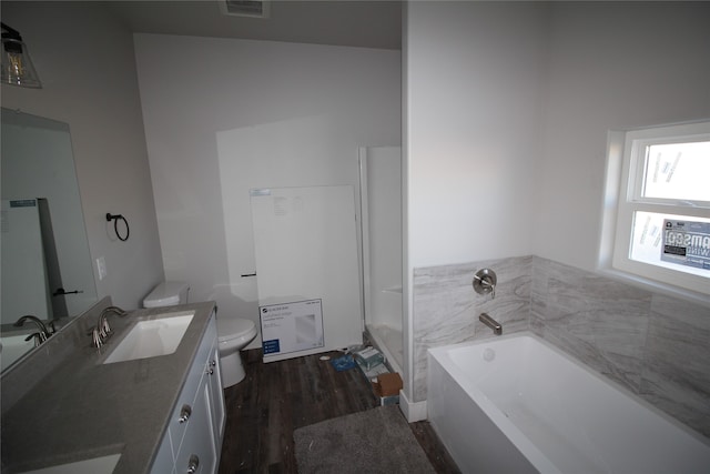 bathroom with toilet, hardwood / wood-style floors, vanity, and a bath