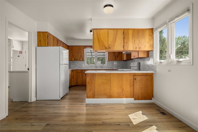 kitchen featuring white appliances, backsplash, kitchen peninsula, and hardwood / wood-style floors