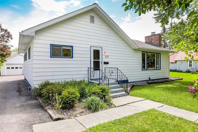 bungalow featuring a front lawn, a garage, and an outdoor structure