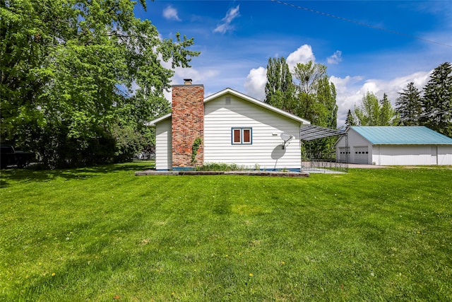 exterior space featuring a garage, a lawn, and an outdoor structure