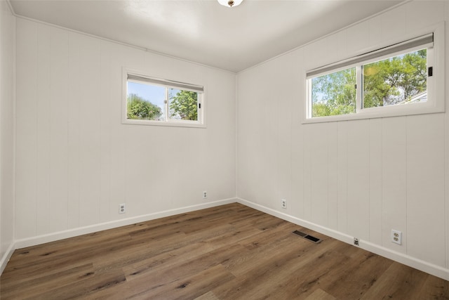 unfurnished room featuring a wealth of natural light and dark hardwood / wood-style flooring