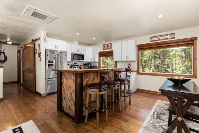 1200 Lost Creek Dr, Kalispell, MT 59901 - kitchen featuring white cabinetry, decorative backsplash, appliances with stainless steel finishes, visible vents, and a kitchen island