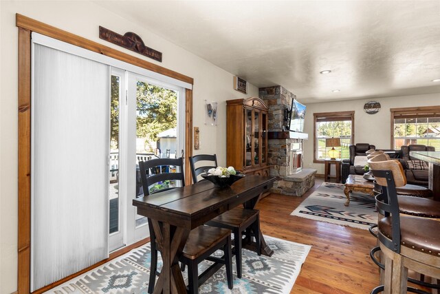 dining room featuring hardwood / wood-style floors and a stone fireplace