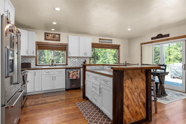 1200 Lost Creek Dr, Kalispell, MT 59901 - kitchen with stainless steel appliances, a breakfast bar, white cabinetry, backsplash, and recessed lighting