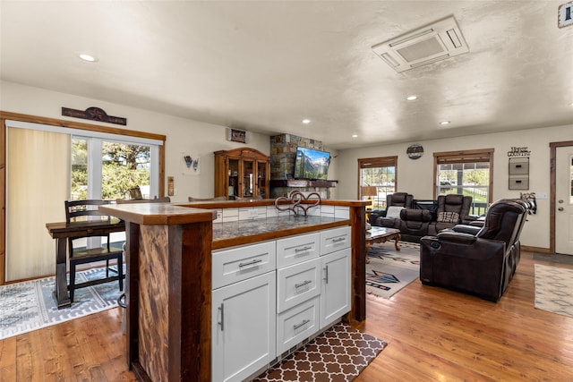 kitchen featuring recessed lighting, visible vents, white cabinets, open floor plan, and light wood finished floors