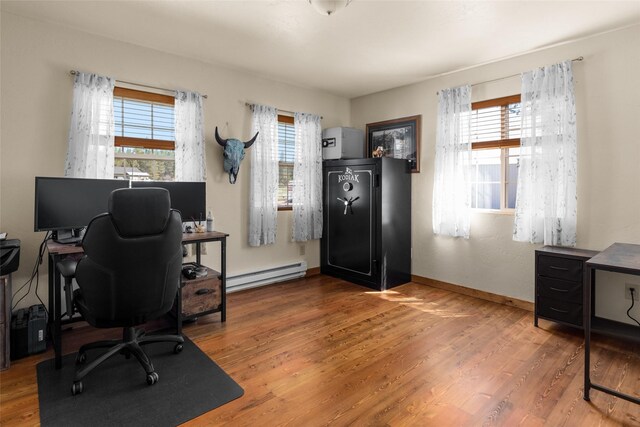 office featuring wood-type flooring, a wealth of natural light, and a baseboard heating unit