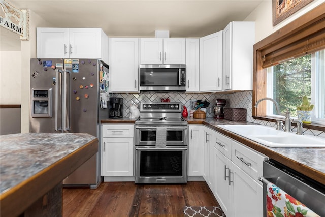 kitchen with appliances with stainless steel finishes, a sink, white cabinets, and decorative backsplash