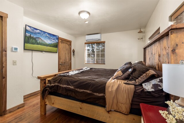 bedroom with hardwood / wood-style flooring and an AC wall unit