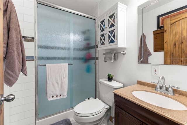 bathroom with vanity, toilet, and a shower with shower door