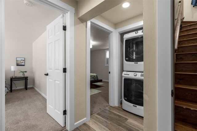 clothes washing area with light hardwood / wood-style floors and stacked washer and clothes dryer