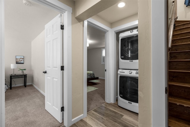 laundry area with carpet floors, stacked washing maching and dryer, baseboards, and laundry area