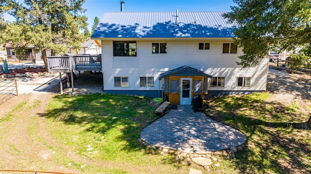 view of front of house featuring metal roof, a wooden deck, and a front lawn