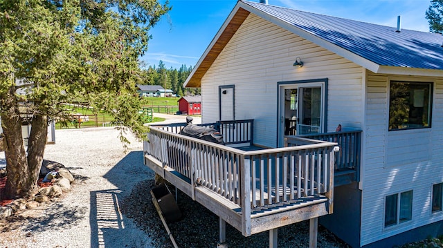 rear view of property with a deck, fence, and metal roof