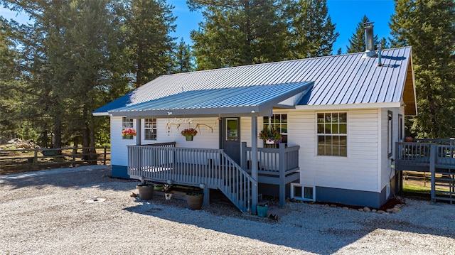 view of front facade featuring covered porch, fence, and metal roof