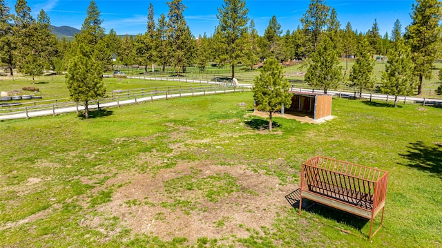 view of property's community with a rural view, fence, and a lawn