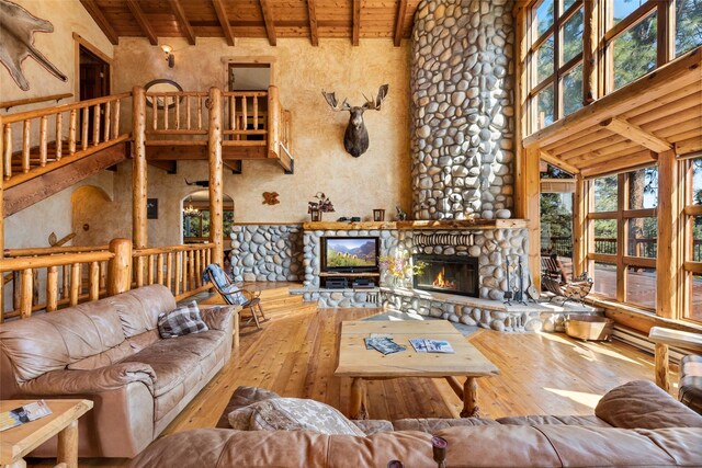 living room with a stone fireplace, high vaulted ceiling, and hardwood / wood-style flooring