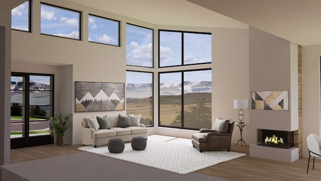 living room with a water and mountain view, plenty of natural light, a towering ceiling, and hardwood / wood-style flooring