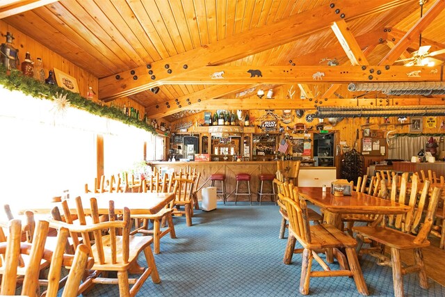 283 Lost Trail Hot Springs Rd, Sula, MT 59871 - carpeted dining room featuring vaulted ceiling with beams, wooden ceiling, and bar area