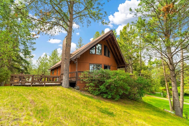 view of side of property featuring a lawn and a wooden deck