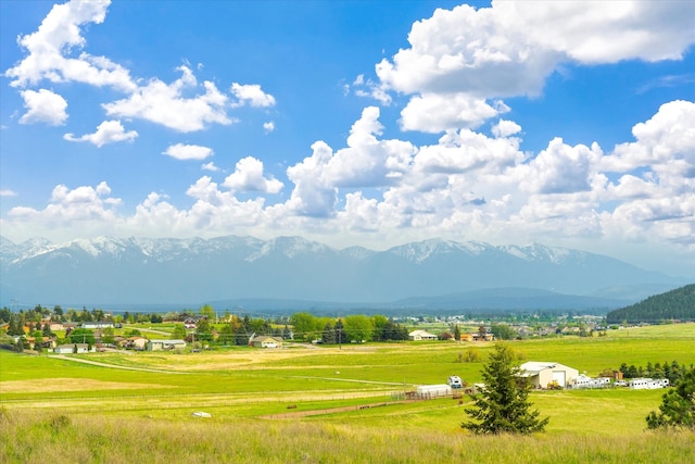 view of property's community featuring a rural view, a lawn, and a mountain view